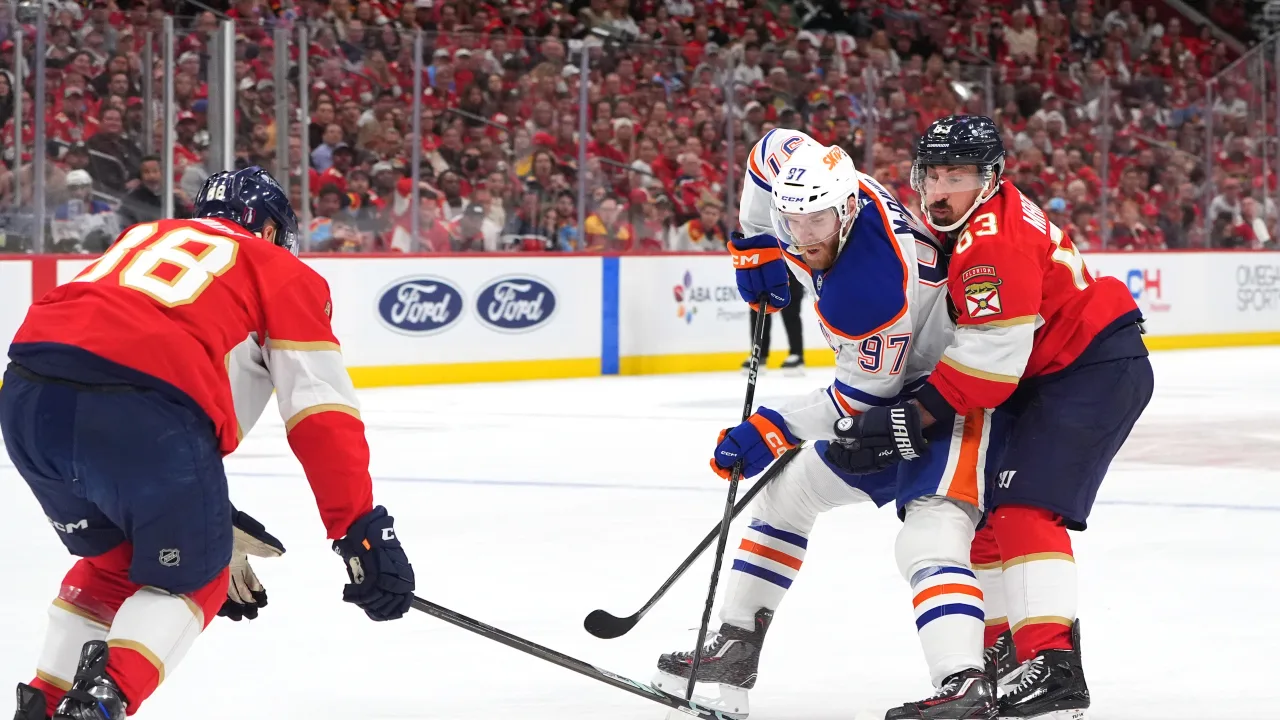 Os jogadores Connor McDavid (97) do Oilers, e Brad Marchand (63) do Panthers, disputam o puck no jogo 3 da final da Stanley Cup, disputada no dia 09/06/2025 na Amerant Bank Arena, em Sunrise, Flórida. Fonte: NHL (2025).