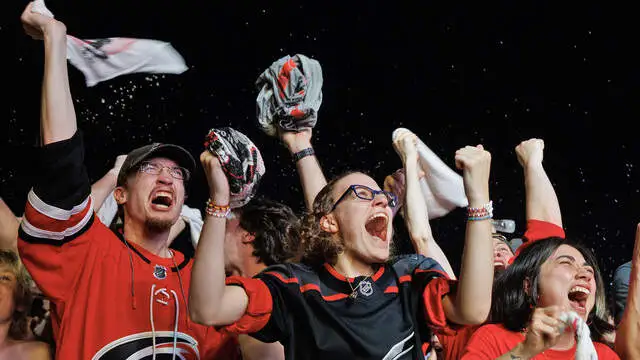 Torcedores do Carolina Hurricanes comemoram em uma watch party do lado de fora do Lenovo Center, em Raleigh, após a equipe abrir 2 a 0 contra o Vegas Golden Knights no Jogo 6 da final da Stanley Cup 2026 – Foto: Kaitlin McKeown / The News & Observer – Fonte: The News & Observer (2026).