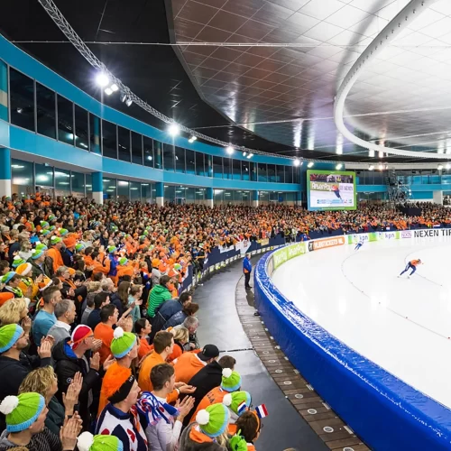 Competição de patinação de velocidade em pista longa, com a grande torcida da Holanda assistindo - Fonte: Olympics (2026)