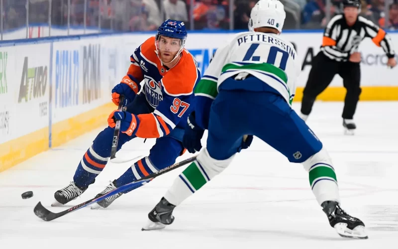 1- Connor McDavid Disputa o puck em jogo contra o Vancouver Canucks em 11/10/2025 – Fonte: NHL (2025)