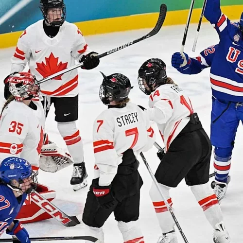 Hilary Knight da equipe dos EUA, comemora o primeiro gol de sua equipe contra Ann-Renee do Canadá durante a disputa pela medalha de ouro do hockey no gelo feminino, entre EUA e Canadá na Milano Santagiulia Ice Hockey Arena, durante os Jogos Olímpicos de Inverno Milano Cortina 2026, em 19/02/2026. FOTO: ALEXANDER NEMENOV/AFP via Getty Images – Fonte: CA Sports (2026).