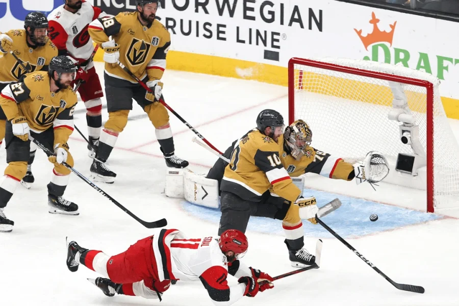Mesmo caindo Jordan Staal (número 11), consegue tocar o puck e fazer o gol, no jogo 4 da final da Stanley Cup 2026 entre as equipes de Vegas e Carolina - CAR@VGK, SCF – Fonte: NHL (2026).