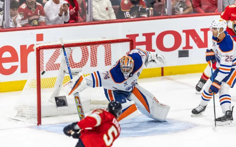 O jogador do Panthers, Aaron Ekblad (5) chuta para o gol de Stuart Skinner, dos Oilers, no jogo 3 da final da Stanley Cup, disputada no dia 09/06/2025 na Amerant Bank Arena, em Sunrise, Flórida. Fonte: NHL (2025).